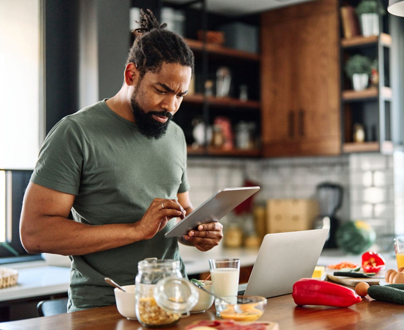Man using tablet in kitchen while cooking.